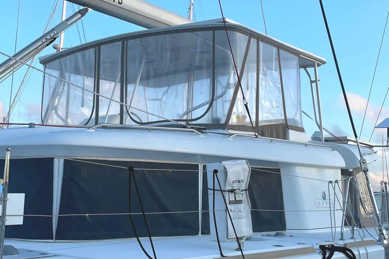 Slide: The Image of 2016 Lagoon 450 F catamaran with enclosed flybridge, docked under clear blue sky. - 5