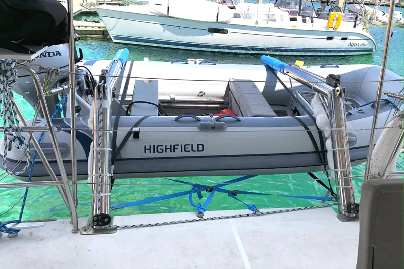 Slide: The Image of Inflatable Highfield boat on Lagoon 450 F catamaran, 2016 model, docked in clear turquoise water. - 9