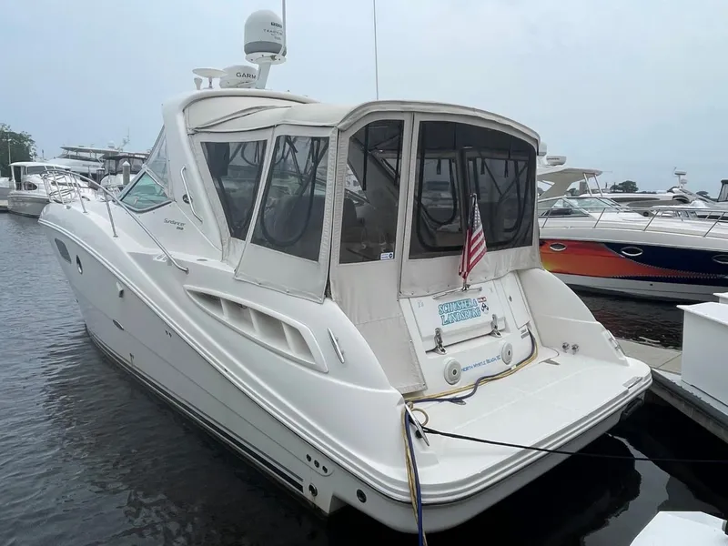 Slide: The Image of 2010 Sea Ray 350 Sundancer yacht docked at marina, rear view with canopy and American flag. - 10