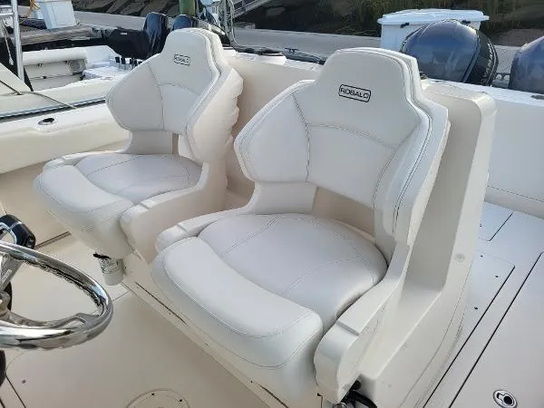 Slide: The Image of 2014 Robalo R 300 boat with white cushioned seats and steering wheel. - 27