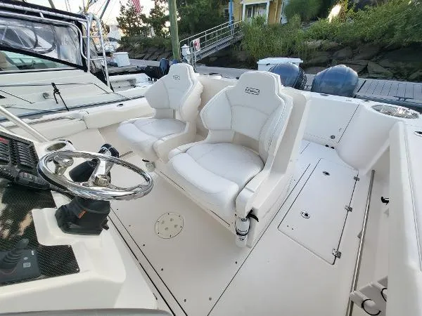Slide: The Image of 2014 Robalo R 300 boat interior with dual white captain seats and steering wheel. - 28