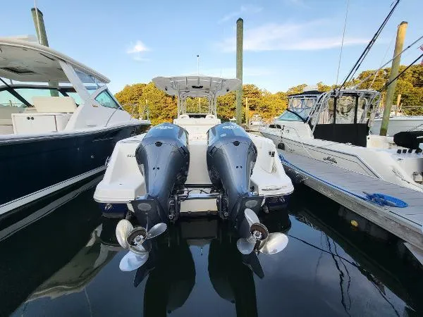Slide: The Image of 2014 Robalo R 300 boat with dual outboard engines docked between two other boats. - 34