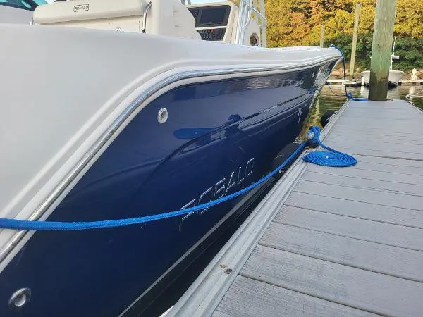 Slide: The Image of 2014 Robalo R 300 boat docked, blue hull, white deck, secured with blue rope. - 5