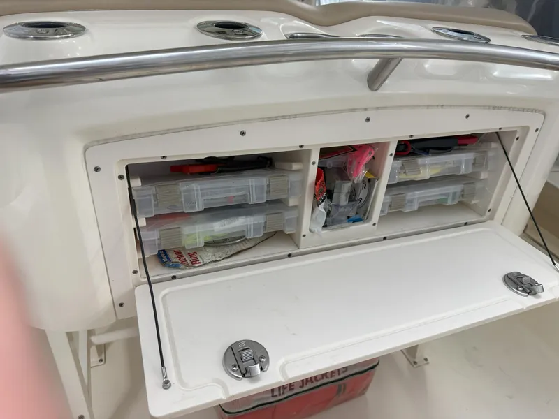 Slide: The Image of 2022 Scout 255 LXF boat storage compartment with organized fishing gear and life jackets. - 18