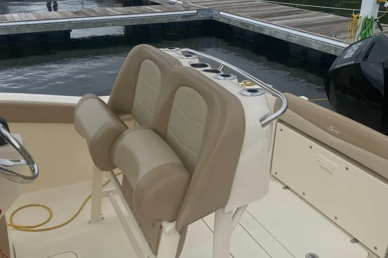 Slide: The Image of 2022 Scout 255 LXF boat interior with tan seating and cup holders at dock. - 25