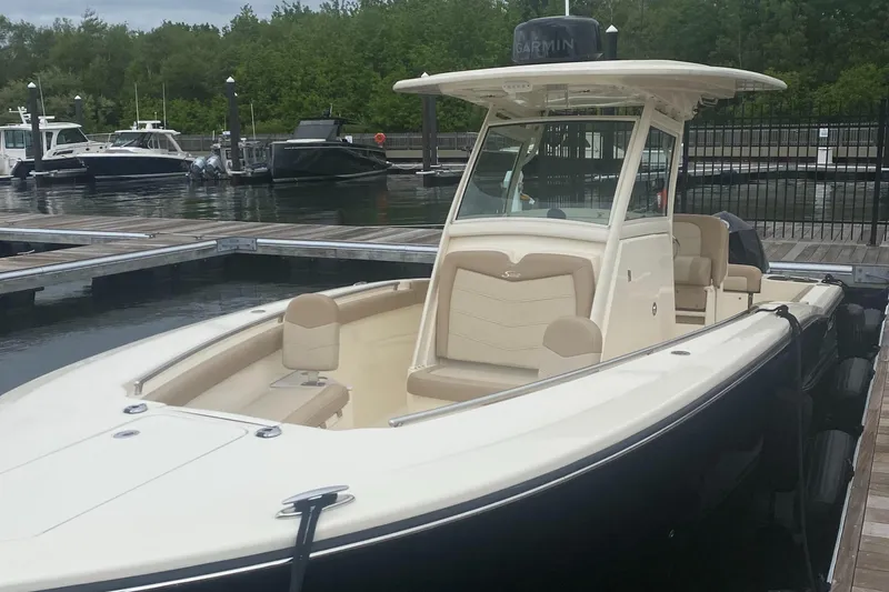 Slide: The Image of 2022 Scout 255 LXF boat docked at marina with lush greenery background. - 4