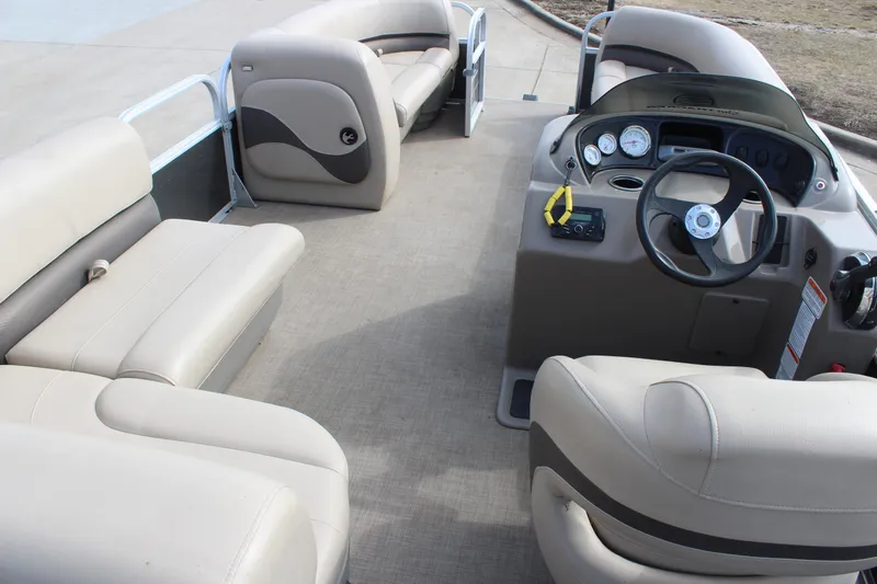 Slide: The Image of 2022 Sun Tracker Party Barge 18 DLX interior with beige seating and steering console. - 7