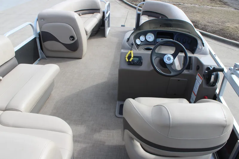 Slide: The Image of 2022 Sun Tracker Party Barge 18 DLX interior with beige seating and steering console. - 8
