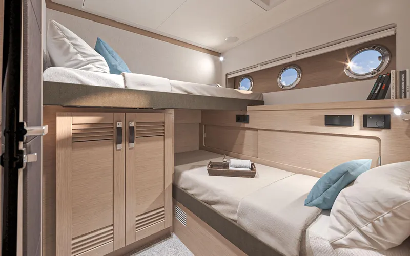 Slide: The Image of 2026 Beneteau Swift Trawler 54 cabin with bunk beds, wooden cabinetry, and porthole windows. - 16