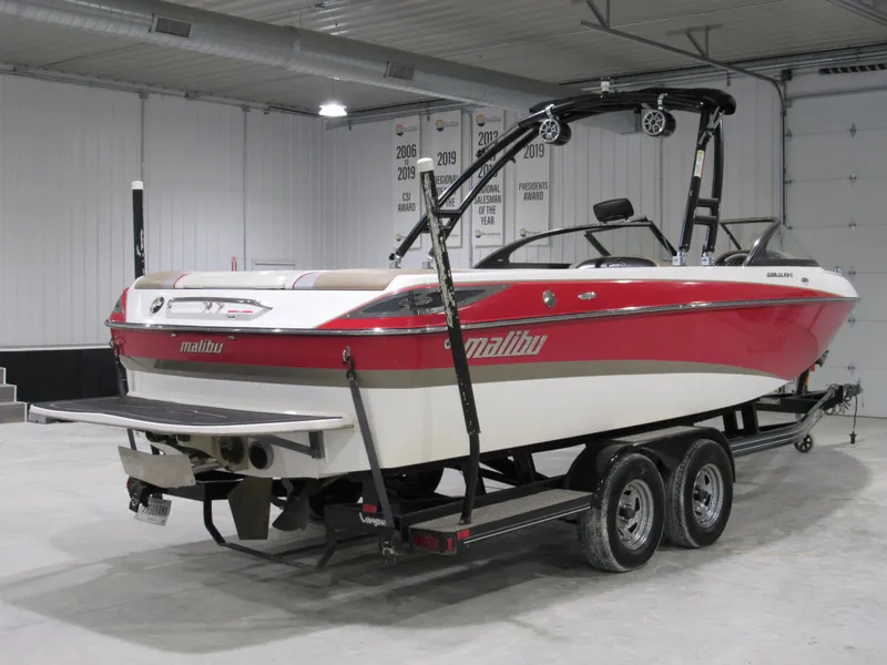 Slide: The Image of 2007 Malibu Wakesetter 247 LSV boat in a garage, red and white design, on a trailer. - 2