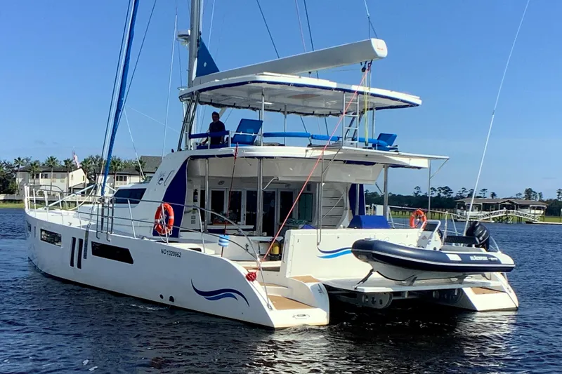 Slide: The Image of 2021 Royal Cape Catamarans Majestic 570 Flybridge on water, featuring spacious deck and tender. - 10