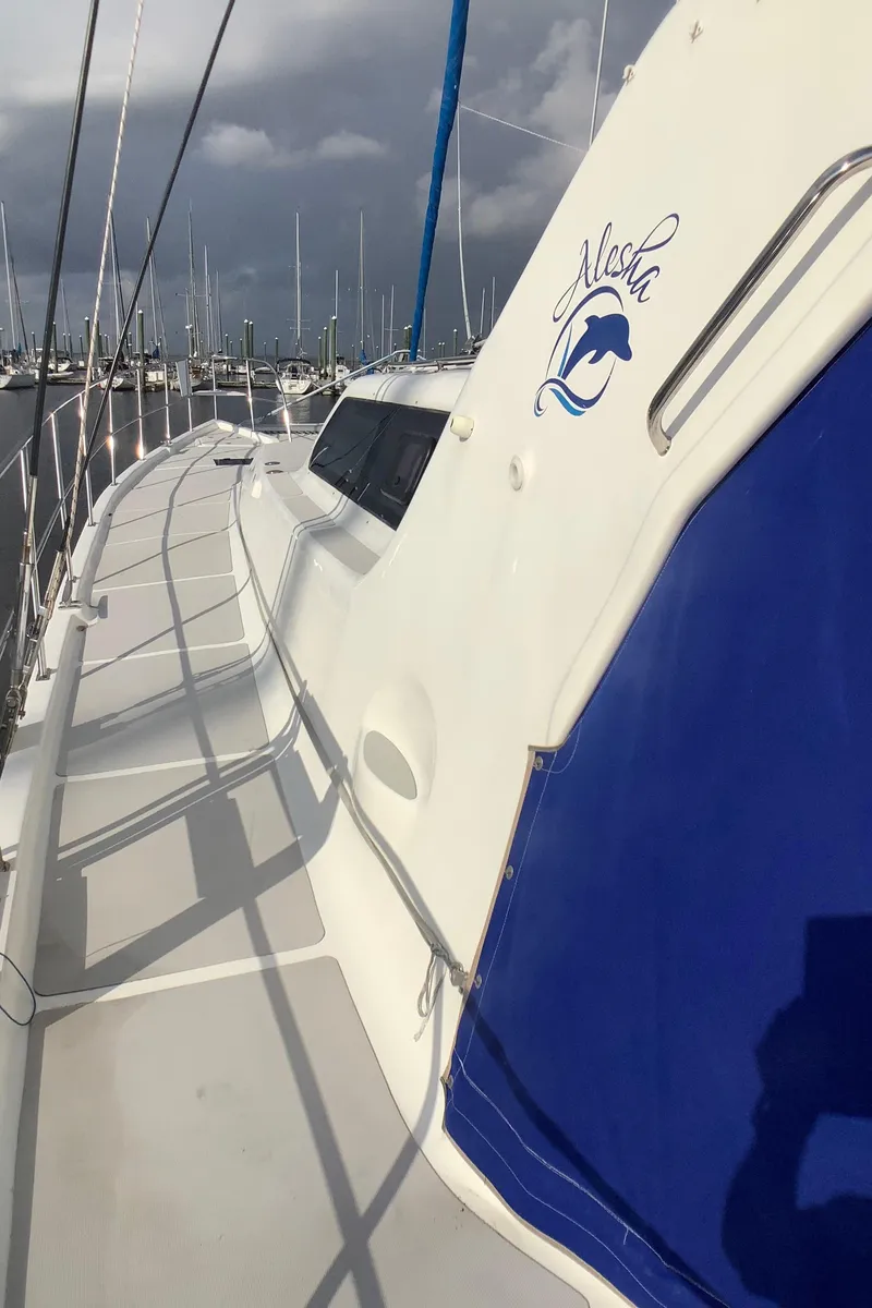 Slide: The Image of Royal Cape Catamarans Majestic 570 Flybridge, 2021 model, docked with blue cover and sleek design. - 6