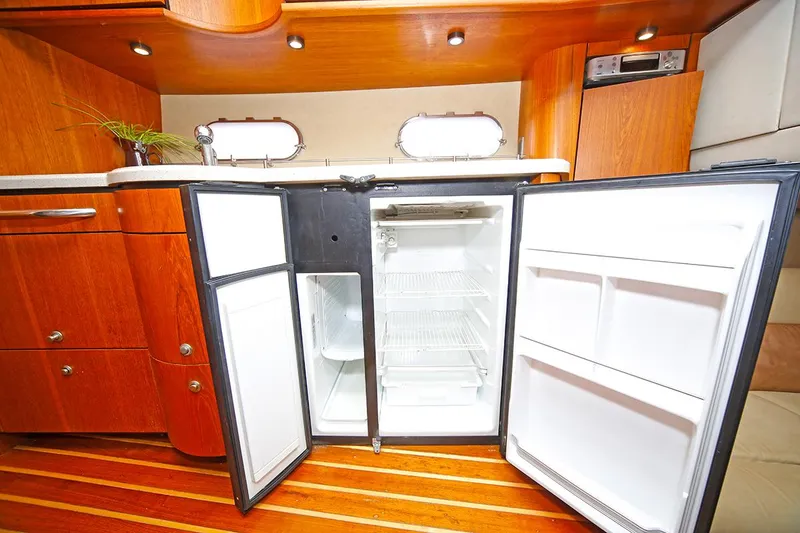 Slide: The Image of 2007 Tiara Yachts 3900 Sovran interior with open refrigerator, wooden cabinetry, and flooring. - 49