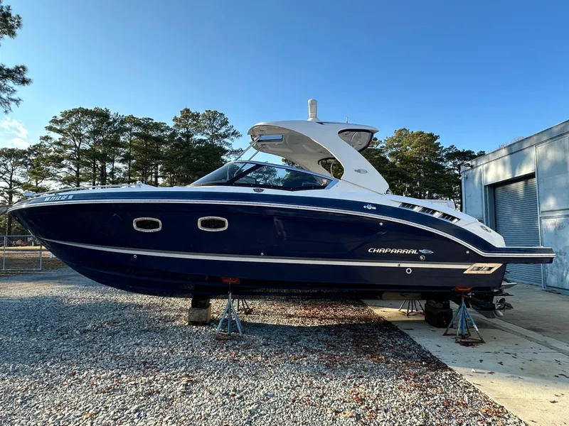 Slide: The Image of 2016 Chaparral 337SSX boat on stands, outdoors, with trees and building in background. - 3