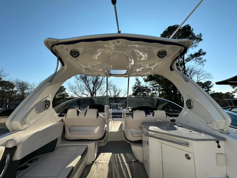 Slide: The Image of 2016 Chaparral 337SSX boat interior with seating and kitchenette under a clear blue sky. - 5