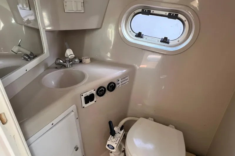 Slide: The Image of 2001 Four Winns 268 Vista boat bathroom with sink, toilet, and porthole window. - 15