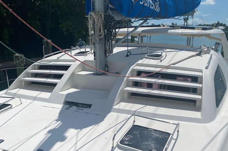 Slide: The Image of 2003 Leopard 38 catamaran deck with blue sail, docked near lush greenery. - 11