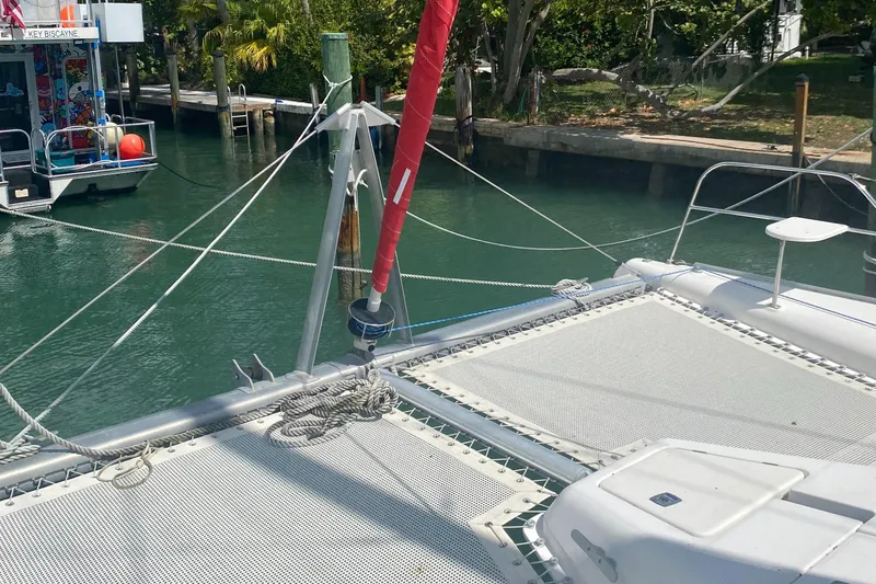 Slide: The Image of Catamaran deck with netting, docked in a marina, surrounded by lush greenery. - 12