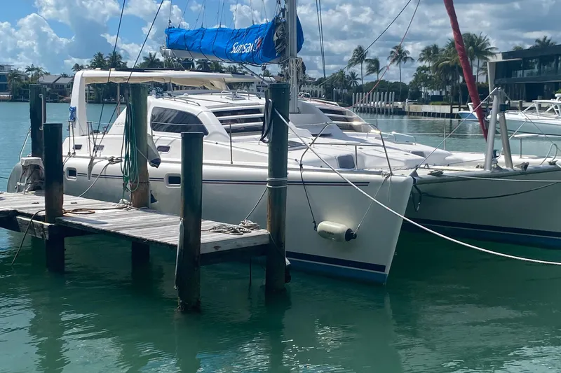 Slide: The Image of 2003 Leopard 38 catamaran docked in a sunny marina with palm trees. - 2