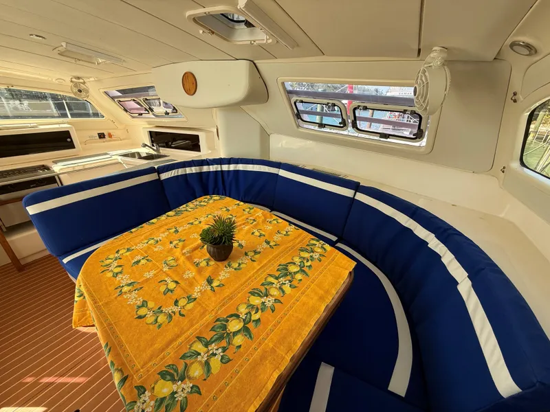 Slide: The Image of Cozy interior of 2003 Leopard 38 yacht with blue seating and vibrant yellow tablecloth. - 29