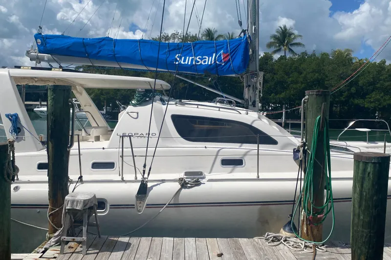Slide: The Image of 2003 Leopard 38 catamaran docked, featuring a blue Sunsail cover and lush tropical backdrop. - 4