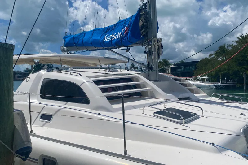 Slide: The Image of 2003 Leopard 38 catamaran docked, featuring a blue sail cover under a partly cloudy sky. - 5