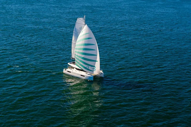 Slide: The Image of 2025 Lagoon 43 catamaran sailing on open blue sea with striped sail. - 48