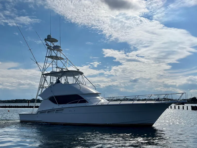 Slide: The Image of 2005 Hatteras 50' Convertible yacht on calm water under a partly cloudy sky. - 2