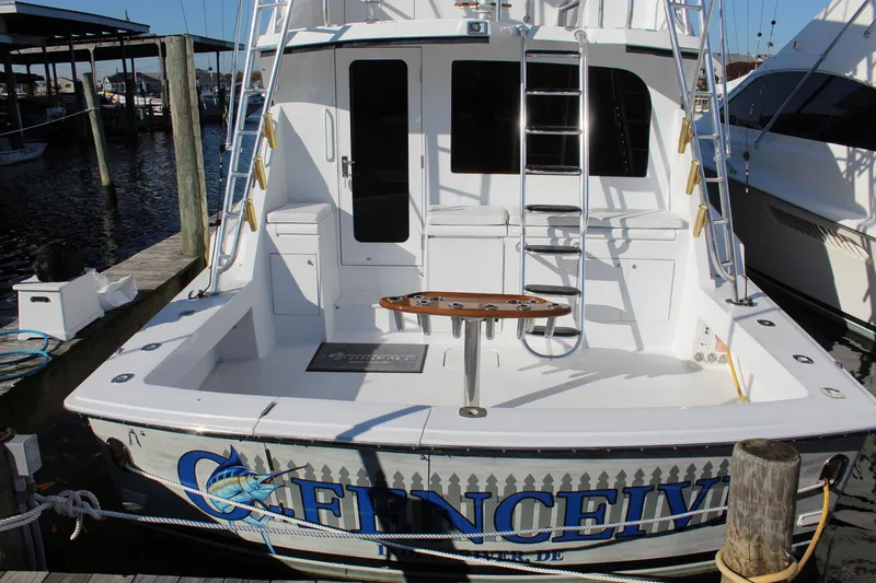 Slide: The Image of 2005 Hatteras 50' Convertible yacht docked, featuring a spacious fishing deck and ladder. - 21