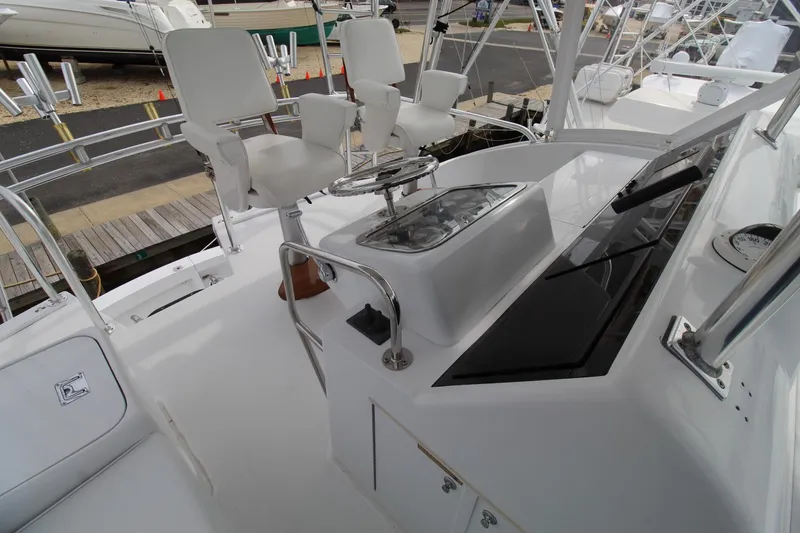Slide: The Image of 2005 Hatteras 50' Convertible yacht helm with white captain's chairs and control panel. - 41