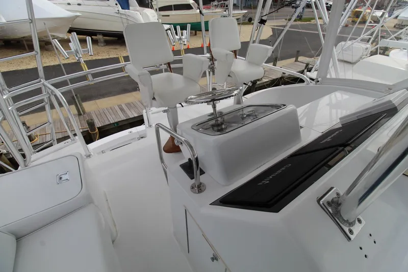 Slide: The Image of 2005 Hatteras 50' Convertible yacht helm with white seating and control panel. - 42