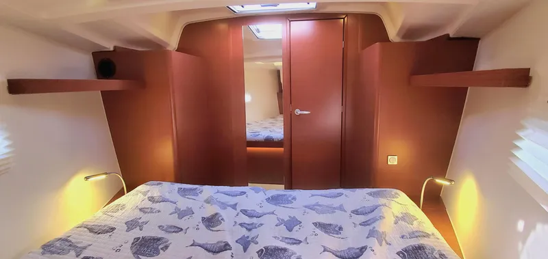 Slide: The Image of Die Kabine der Hanse 388 von 2024 zeigt ein gemütliches Bett mit Fischmusterdecke und warmem Holzdekor. - 15