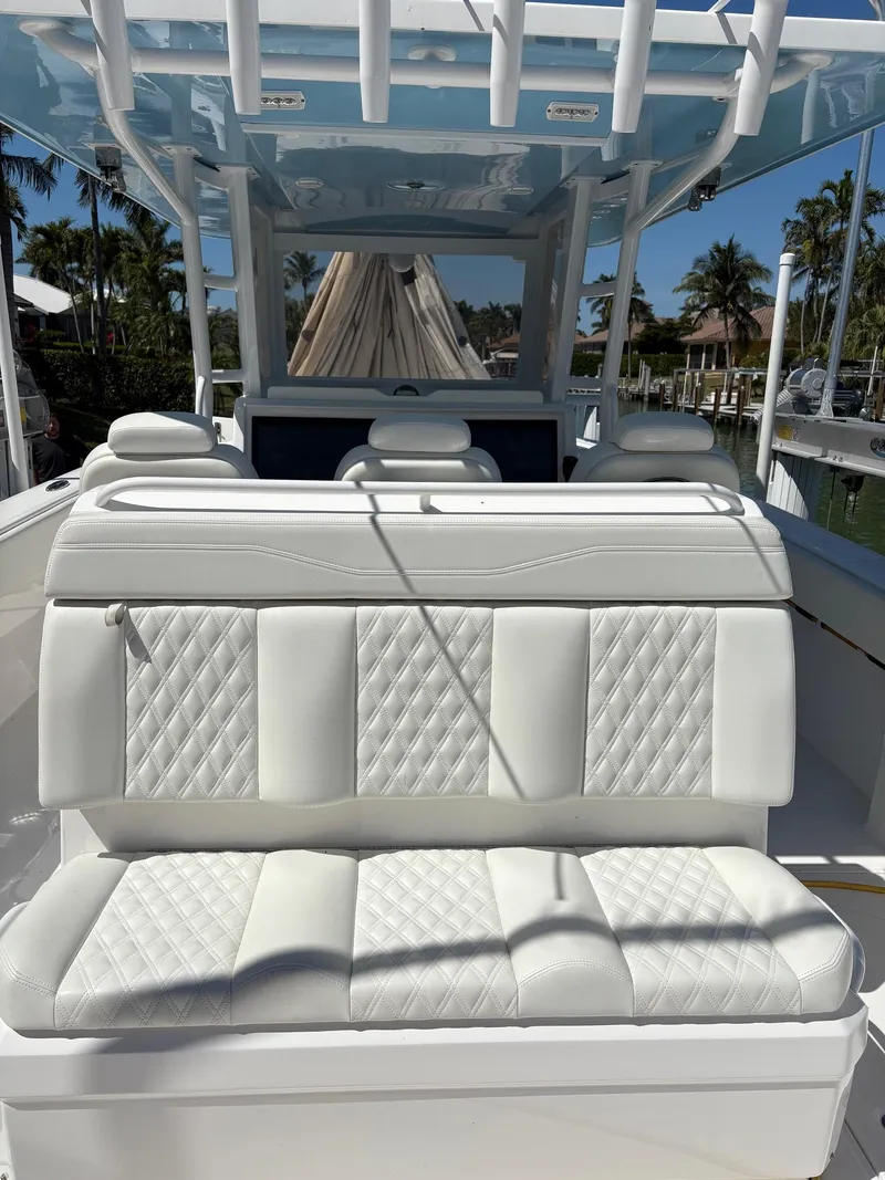 Slide: The Image of 2020 Invincible 40 Catamaran interior with white quilted seating, docked near palm trees. - 10