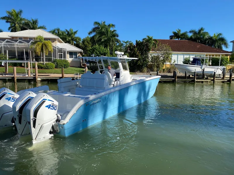 Slide: The Image of Invincible 40 Catamaran 2020 in blue, docked near waterfront homes, with twin 450 engines. - 4