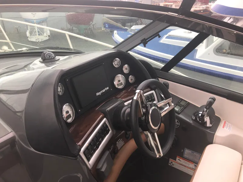 Slide: The Image of 2018 Four Winns V355 boat helm with steering wheel and navigation controls. - 11