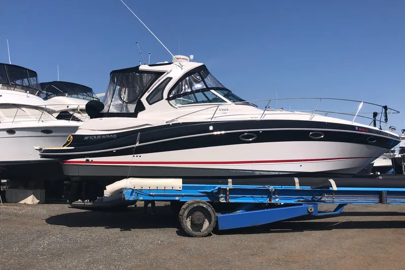 Slide: The Image of 2018 Four Winns V355 boat on trailer, side view, under clear blue sky. - 2