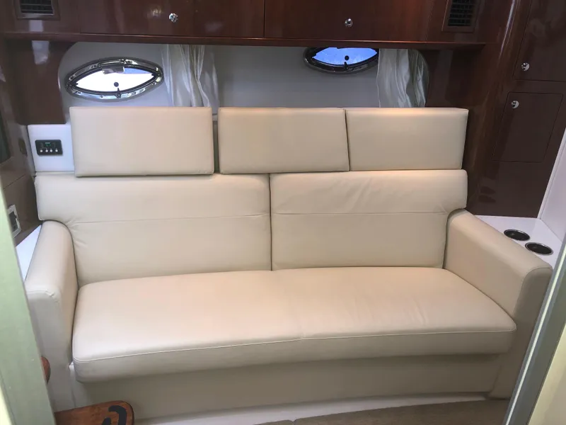 Slide: The Image of Luxurious beige sofa in 2018 Four Winns V355 yacht interior, with wooden accents and porthole windows. - 20