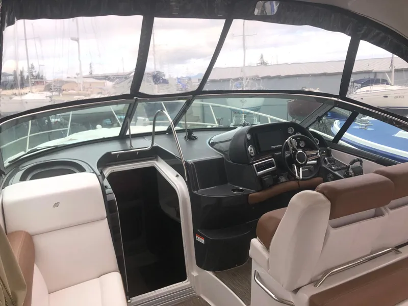 Slide: The Image of 2018 Four Winns V355 boat interior with helm, seating, and marina view. - 6