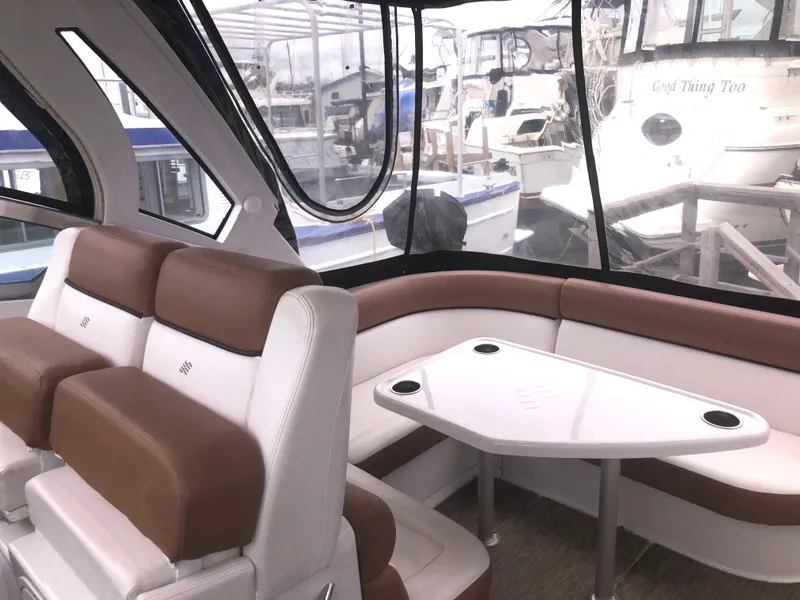 Slide: The Image of 2018 Four Winns V355 boat interior with brown and white seating, and a sleek table. - 9