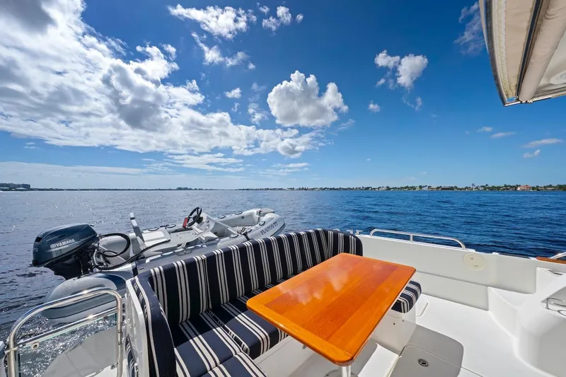 Slide: The Image of 2019 Sabre 45 Salon Express yacht with striped seating, wooden table, and scenic ocean view. - 59