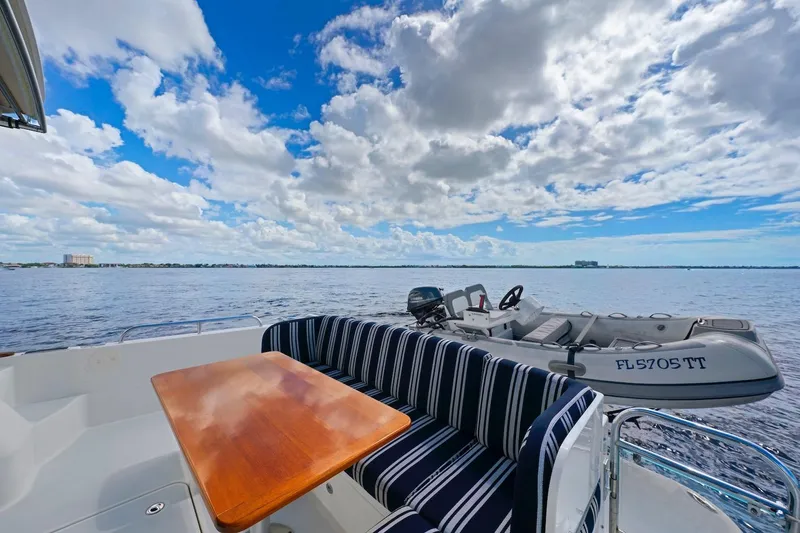 Slide: The Image of 2019 Sabre 45 Salon Express yacht deck with table, striped seating, and ocean view. - 61