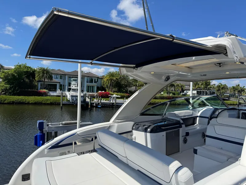 Slide: The Image of 2023 Formula 350 Crossover Bowrider with canopy, docked by waterfront homes. - 10