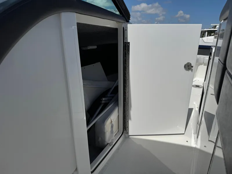 Slide: The Image of 2023 Formula 350 Crossover Bowrider storage compartment with open door under clear sky. - 43