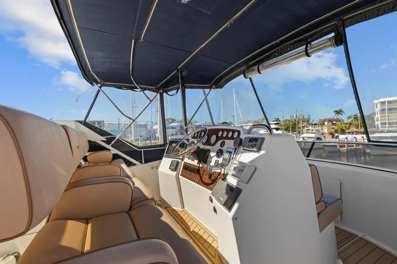 Slide: The Image of 2000 Silverton 392 Motor Yacht helm with tan seating and marina view. - 5