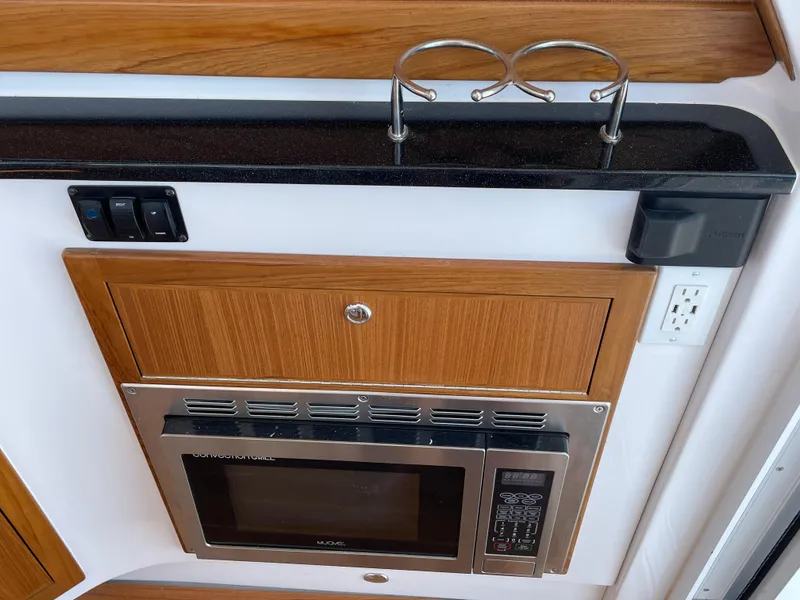 Slide: The Image of Interior of 2025 True North 34 Outboard Express with microwave and wooden cabinetry. - 29