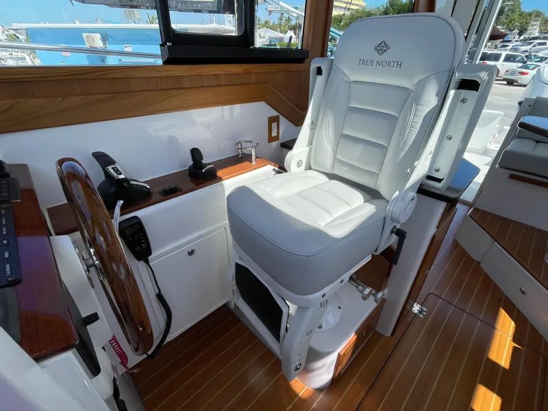 Slide: The Image of Captain's chair in 2025 True North 34 Outboard Express boat cockpit, featuring wood accents. - 33
