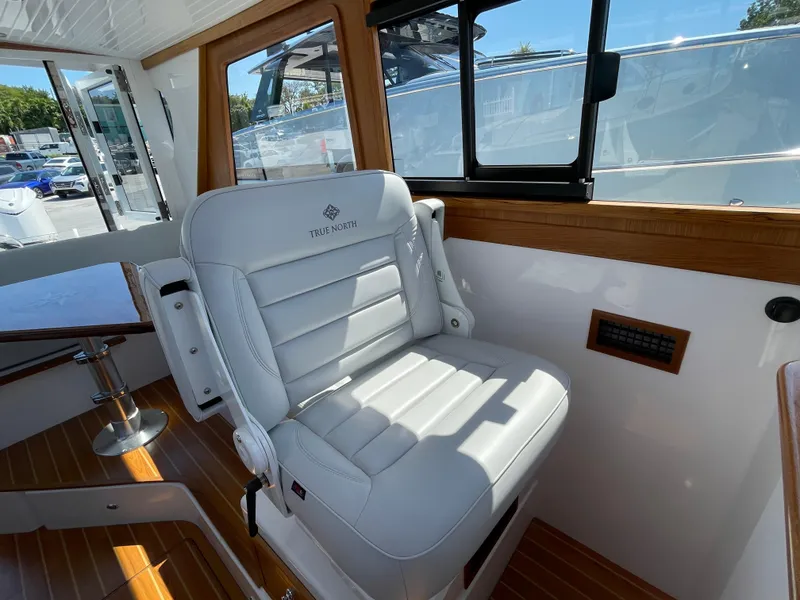 Slide: The Image of 2025 True North 34 Outboard Express boat interior with white seating and wooden accents. - 34