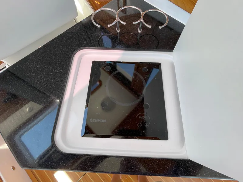 Slide: The Image of True North 34 Outboard Express 2025 boat kitchen with Kenyon cooktop and cup holders. - 39