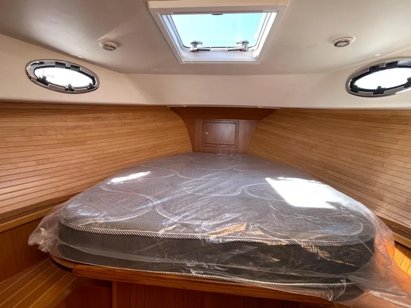 Slide: The Image of 2025 True North 34 Outboard Express cabin with bed, wooden interior, and skylight. - 43