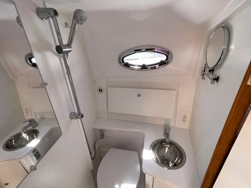 Slide: The Image of 2025 True North 34 Outboard Express boat bathroom with modern fixtures and porthole window. - 47
